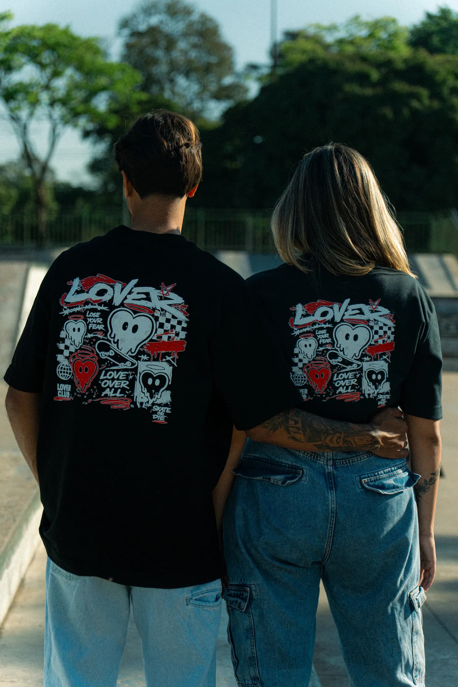 Costas de duas camisetas pretas com a estampa completa do DROP 01.