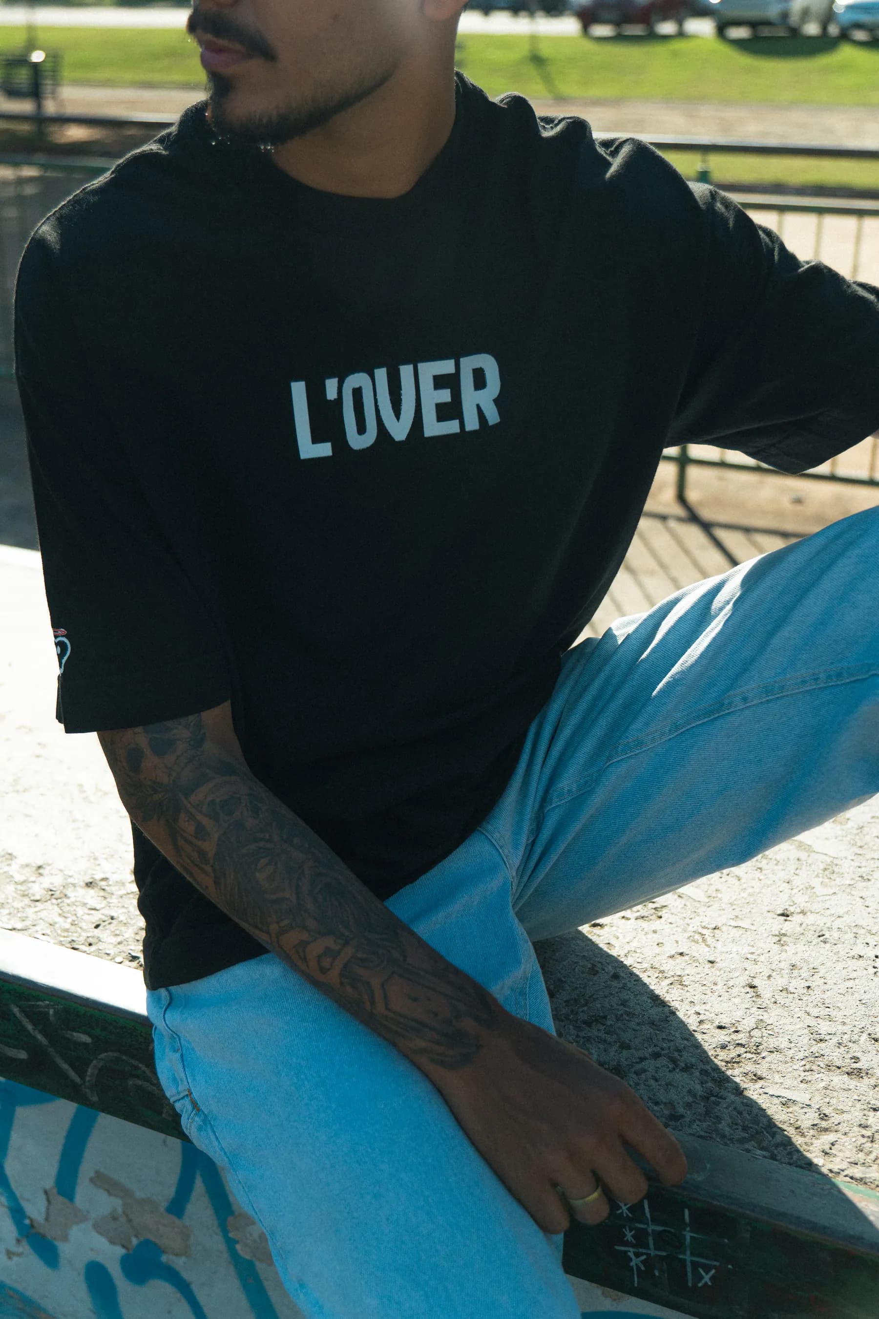Detalhe do peito da camiseta preta com o wordmark L'OVER estampado.